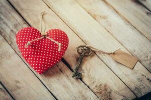 coração tecido e vintage chave com tag em madeira mesa fundo. foto
