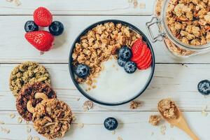 tigela do granola com iogurte, fresco bagas, morango em madeira mesa. foto