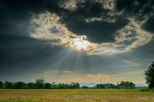 campo agricultura e chuva nuvens com raios solares foto