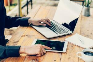 homem usando tábua e computador portátil em mesa dentro café fazer compras. foto