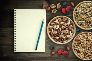 caseiro granola e fresco bagas em madeira mesa com Nota livro, cópia de espaço. foto