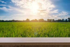 madeira mesa e espaço para produtos exibição montagem com arroz campo e pôr do sol. foto