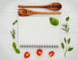 caderno espiral com ervas frescas e tomates foto