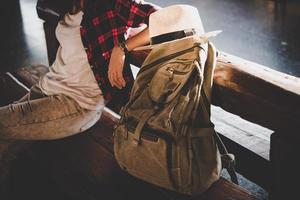 jovem hippie turista com mochila sentada na estação de trem foto