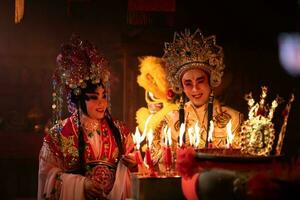 masculino e fêmea chinês ópera atores luz uma vela para orar homenagem para a Deuses para realçar a prosperidade para você mesmo em a ocasião foto