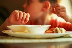 Garoto comendo velozes Comida dentro uma cafeteria. a criança comendo francês fritas com pepitas foto