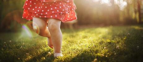garotas nu pés dentro a verde grama. pequeno feliz criança corrida às pôr do sol descalço ar livre. foto