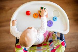 a criança tocam a pirâmide. criança dentro a crianças quarto jogando com brinquedos Visão a partir de acima foto