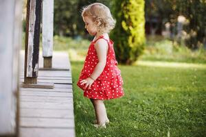 pequeno menina jogando sozinho dentro a jardim foto