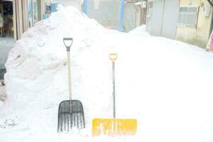 neve colher e varredores colocar dentro frente do uma grande amontoar neve. foto