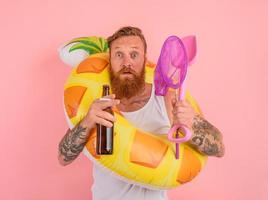 receoso homem é pronto para nadar com uma rosquinha salva-vidas com Cerveja e cigarro dentro mão foto