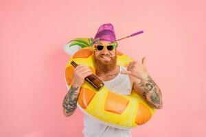 feliz homem é pronto para nadar com uma rosquinha salva-vidas com Cerveja e cigarro foto