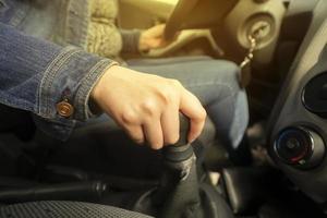 fechar acima do uma mulher mão em a engrenagem alavanca do dela veículo enquanto dirigindo foto