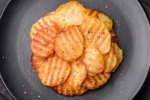 delicioso crocantes frito batatas dentro fatias em uma Preto cerâmico prato foto