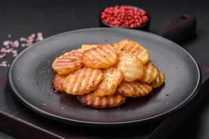 delicioso crocantes frito batatas dentro fatias em uma Preto cerâmico prato foto