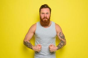 homem com barba e tatuagens mostra com orgulho dele músculo foto
