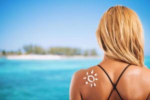 menina dentro roupa de banho com uma Sol fez com protetor solar foto