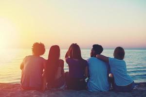 grupo do feliz amigos relaxante às a de praia foto