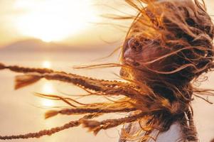 mulher com cabelo sopro dentro a vento durante pôr do sol foto