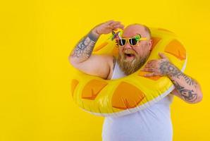 gordo feliz homem com peruca dentro cabeça é pronto para nadar com uma rosquinha salva-vidas foto