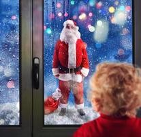 criança observa santa claus através a janelas foto