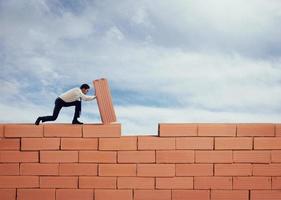 homem de negocios coloca uma tijolo para Construir uma muro. conceito do Novo negócios, parceria, integração e comece foto