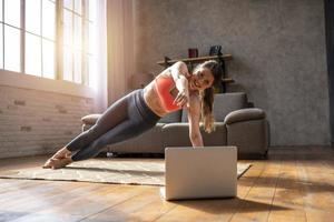 jovem mulher segue com uma computador portátil uma Academia exercícios. ela é às casa vencimento para coronavírus codiv-19 quarentena foto