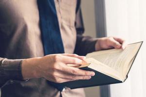 o negócio homem mão segurando livro e lendo às janela. foto