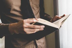 homem de negocios segurando livro às janela. criativo o negócio comece ideia. foto