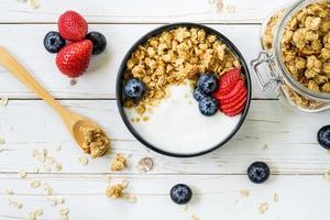 tigela do granola com iogurte, fresco bagas, morango em madeira mesa. foto