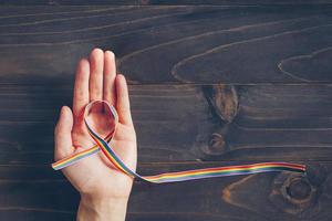 arco Iris fita consciência em mão humano para lgbt conceito em de madeira fundo. foto