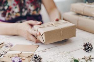 fechar acima do mãos mulher presente presente caixa em de madeira mesa com natal decoração. foto