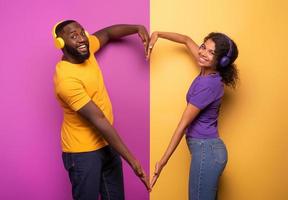 casal com fone de ouvido ouço para música e faço a forma do coração com braços. tolet e amarelo fundo foto