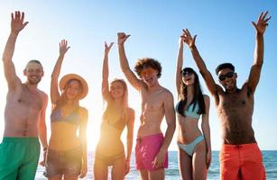 grupo do amigos tendo Diversão em a de praia foto