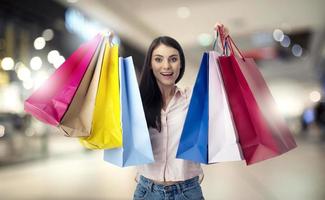 feliz mulher com compras bolsas dentro mão foto