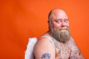 gordo feliz homem com barba , tatuagens e asas atos gostar a anjo foto