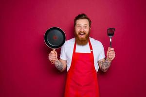 feliz chefe de cozinha com barba e vermelho avental é pronto para cozinhar foto