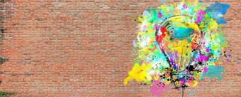 grande estilizado luz lâmpada em uma grande parede do tijolos desenhado com salpicos do colori pintar. conceito do inovação e criatividade tijolo foto