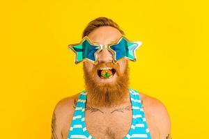 homem com barba e oculos de sol come uma morango foto