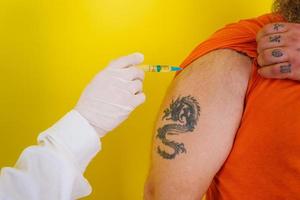 homem com barba e tatuagens faz covid-19 vacina foto