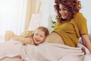 grávida mãe tocam com dela filha. conceito do família, alegria e gravidez foto