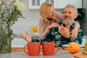 marido e esposa estão abraçando às casa durante café da manhã foto