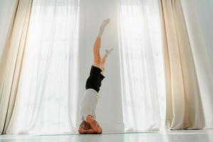 esportivo homem faz ioga exercício às casa foto