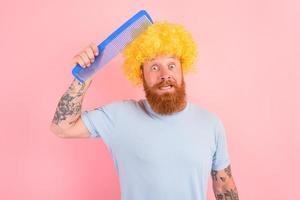 duvidoso homem com barba, amarelo peruca e grande pente foto