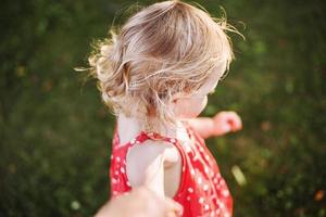 lindo bebê cabelo. a criança detém a mão do a pai e tocam foto