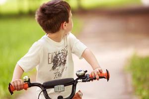 a Garoto é equitação uma bicicleta em a rua foto