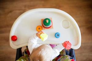 a criança tocam a pirâmide. criança dentro a crianças quarto jogando com brinquedos Visão a partir de acima foto