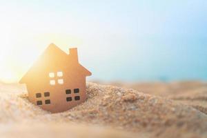 close-up de uma minúscula casa modelo na areia com luz do sol foto