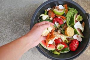 doméstico desperdício para composto a partir de frutas e legumes. mulher lança lixo. foto