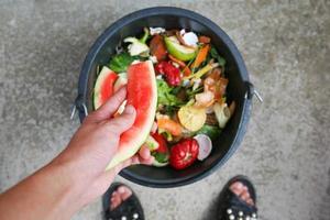 doméstico desperdício para composto a partir de frutas e legumes. mulher lança lixo. foto